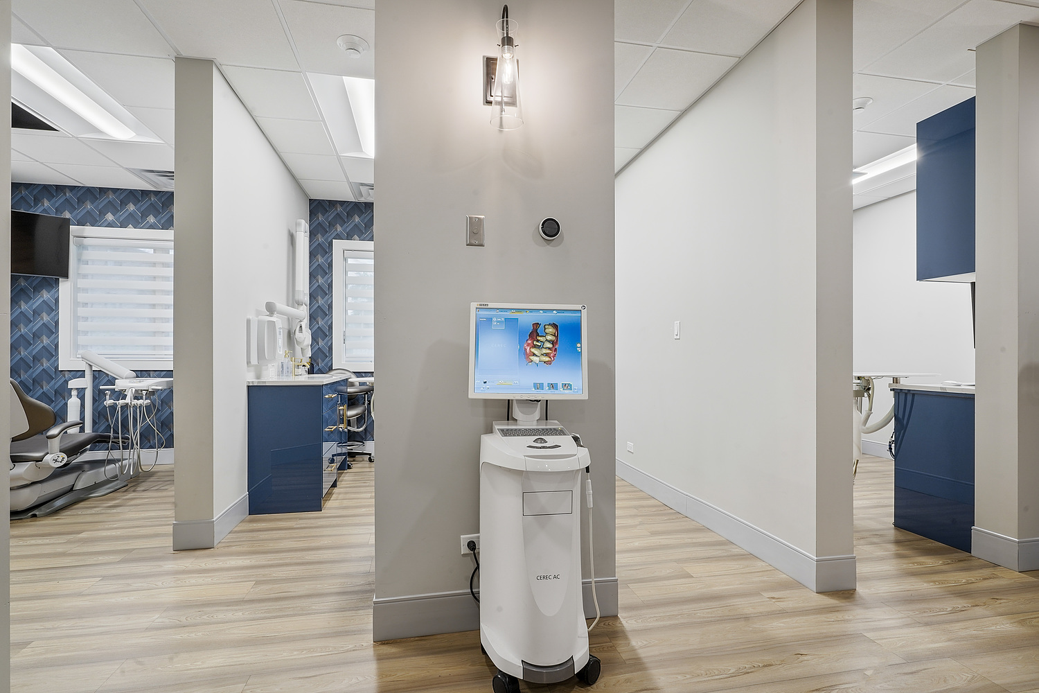An interior view of a modern dental office with a reception area, waiting room, and a dental chair in the background.