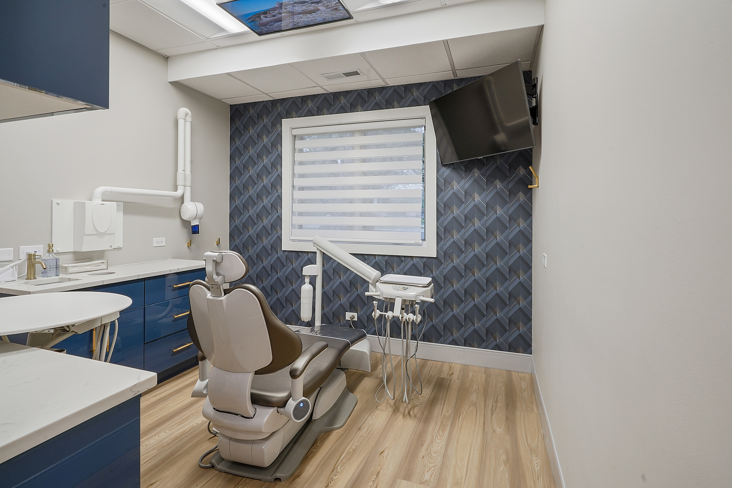 A dental office interior with a modern design, featuring a reception desk, dental chair, and equipment.