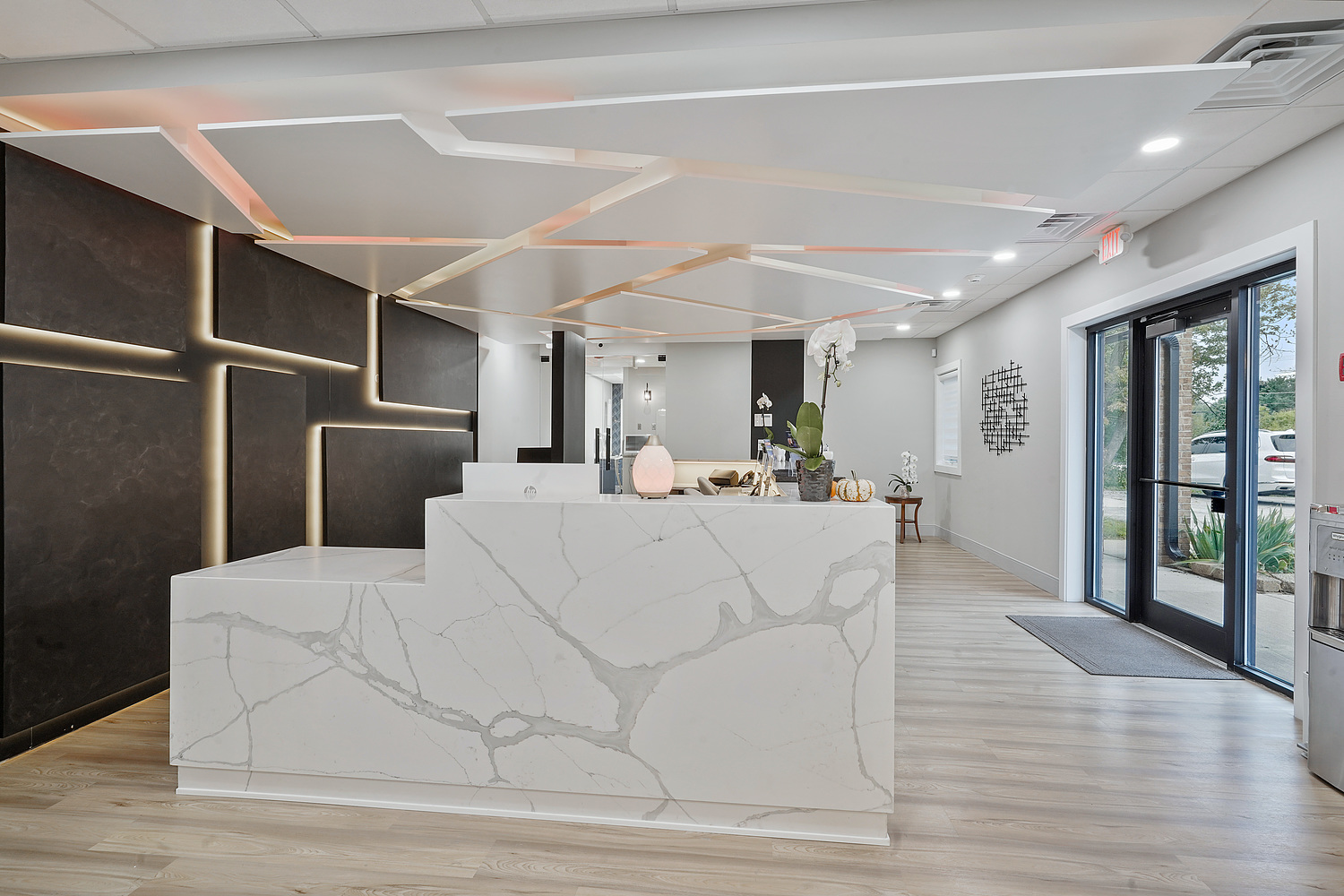 The image shows a modern interior space with a marble countertop, a reception desk area, and a sign with inspirational text.