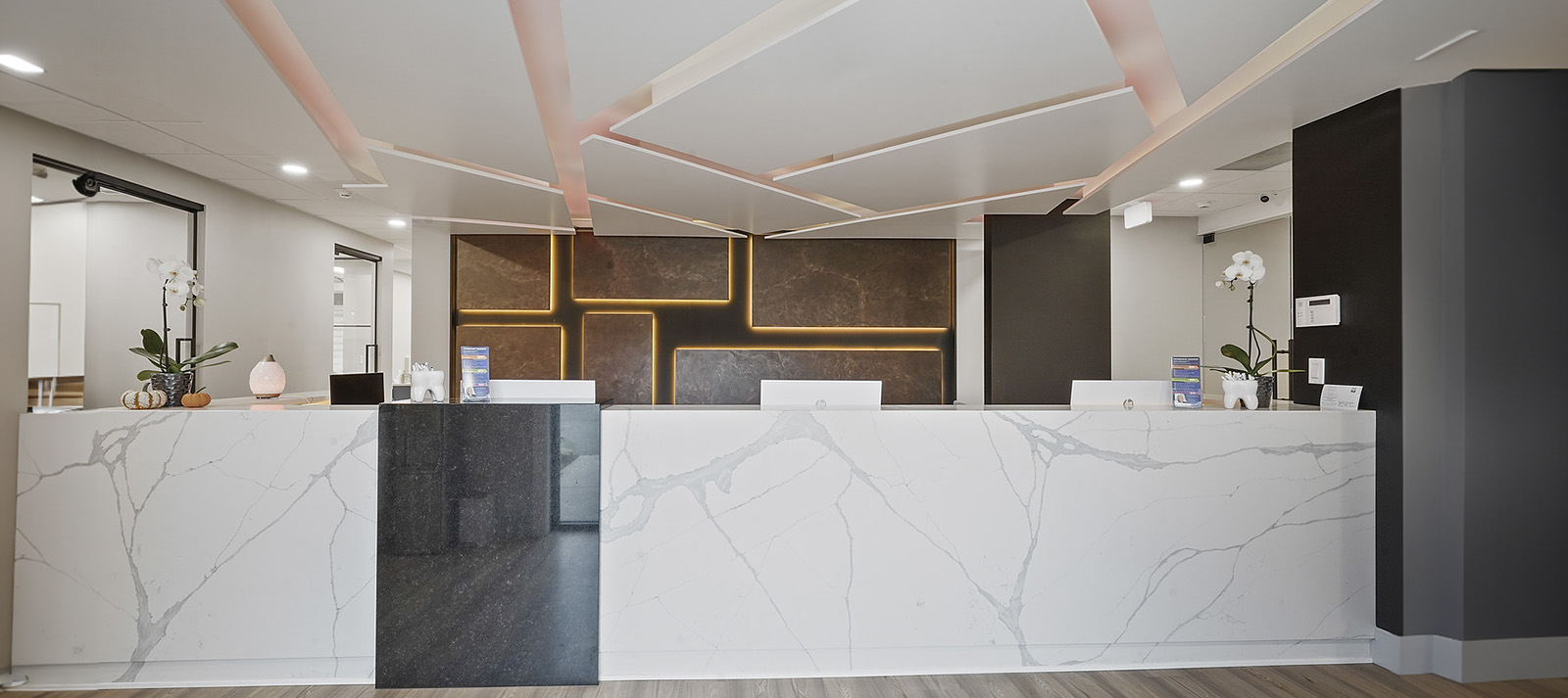 The image depicts a modern interior of an office space with a reception area, featuring marble countertops and a contemporary design.