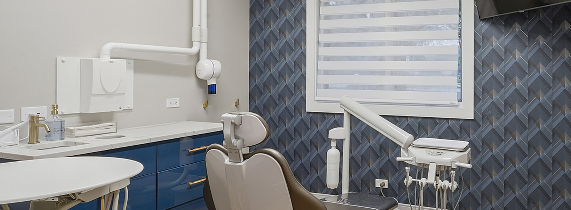 A modern dental practice interior, featuring a clean and organized reception area with a blue and white patterned wall, a large window, and a well-equipped dental office.