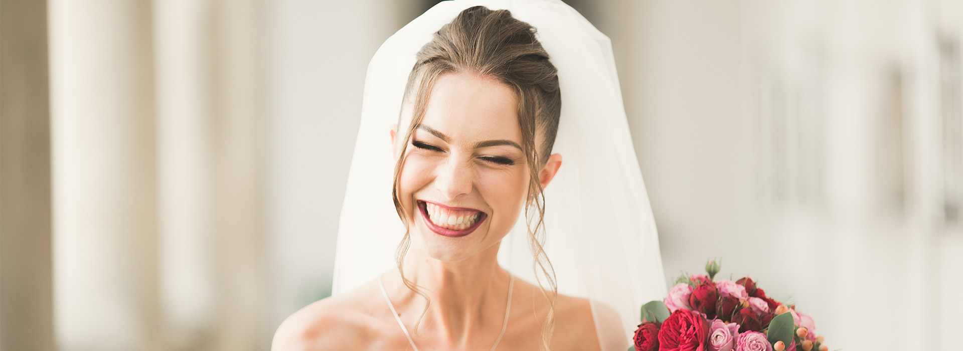 The image shows a bride wearing a white veil and holding a bouquet, smiling at the camera.