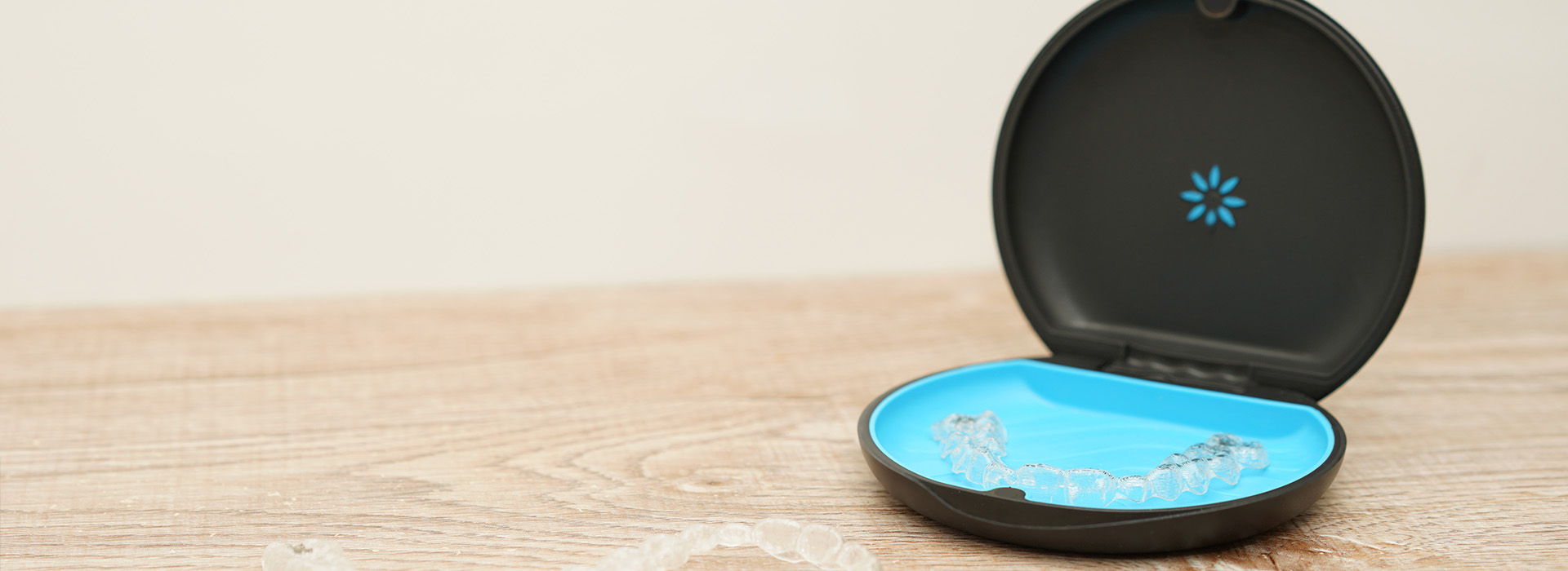 An image of a small, black smart device with a blue circular screen and a camera lens on top, placed against a white background.