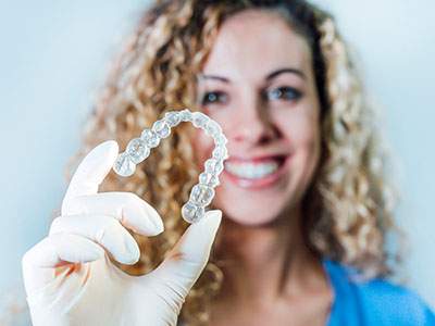 A woman holding a transparent dental retainer.