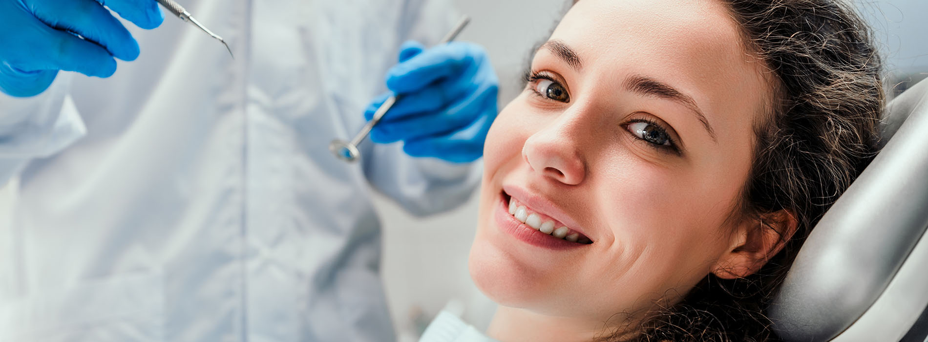 The image shows a woman lying down in a dental chair, receiving dental treatment.