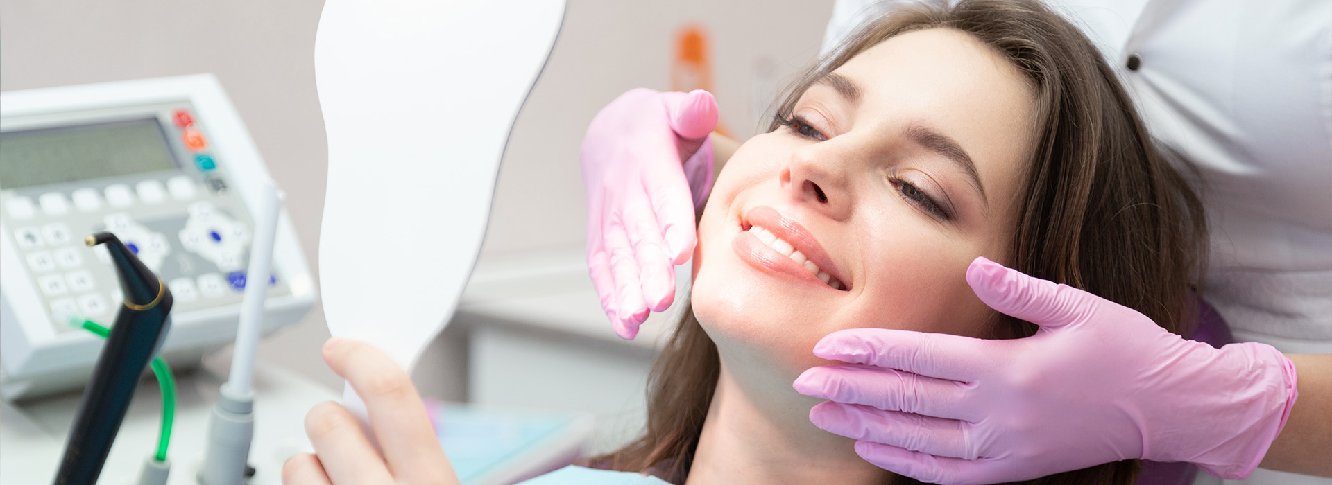 A woman receiving dental care, with a dentist performing an examination and a dental hygienist cleaning her teeth.