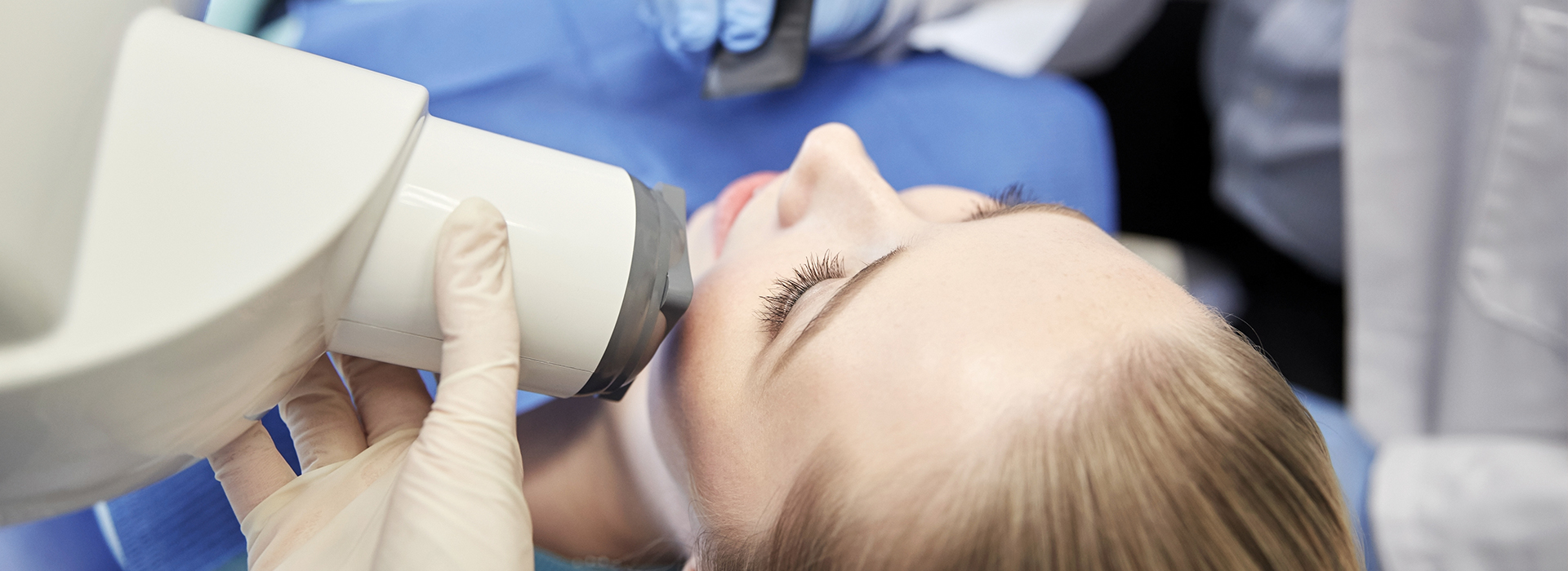 A person receiving a dental implant procedure, with a dentist using a microscope to guide the placement of the implant.