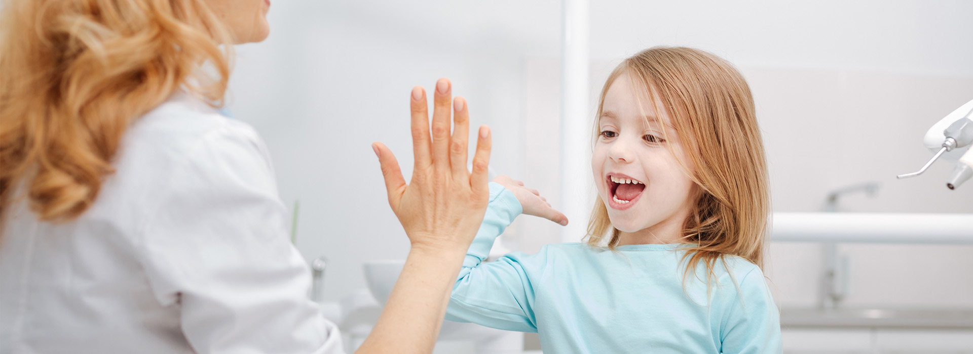 A woman and a young girl are in a bathroom, with the woman interacting with the child.