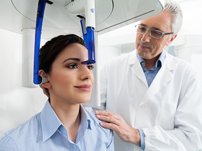 A medical professional examines a patient s head with a specialized device.