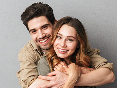 A man and a woman are embracing each other with smiles, posing for a portrait.