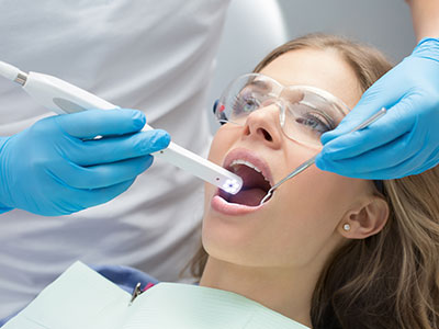 A dental professional using a digital device to examine a patient s mouth during a dental examination.