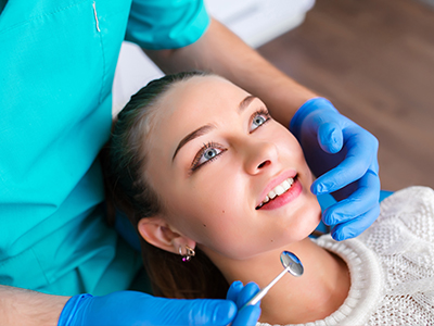 The image shows a person receiving dental care, with a dentist performing a procedure on the individual s teeth.